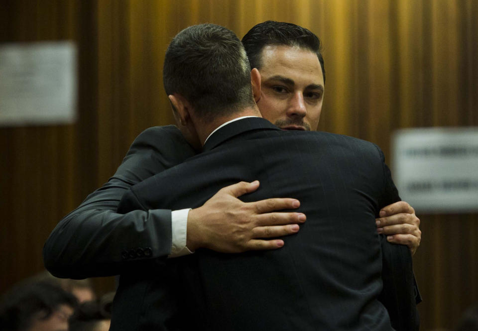 Oscar Pistorius, front, gets a hug from his brother, Carl, back, in court in Pretoria, South Africa, Thursday, April 17, 2014. Pistorius is charged with the murder of his girlfriend, Reeva Steenkamp, on Valentines Day in 2013. (AP Photo/Alet Pretorius, Pool)