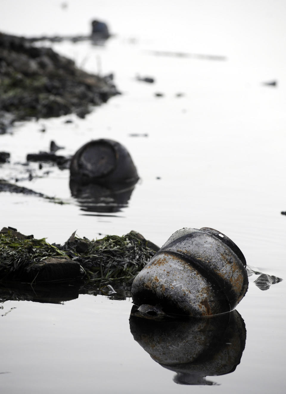 A burned propane tank floats with other debris in a creek near the Tennessee River at the scene of a fatal marina fire at Scottsboro, Ala., on Tuesday, Jan. 28, 2020. Protective boom has been installed to contain fuel and chemicals following a dock blaze that killed several people at Jackson County Park Marina. (AP Photo/Jay Reeves)