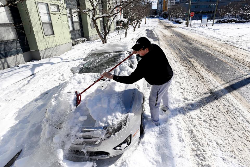 Vanderbilt University student Warner Myntti brushes snow off his car along 18th Avenue on Jan. 16 in Nashville.