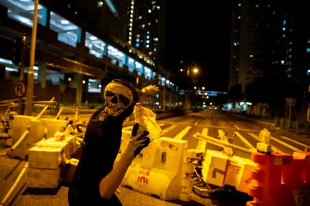 Anti-govenrment protesters throws a molotov cocktail toward riot police officers during a protest at Tseung Kwan O district, in Hong Kong