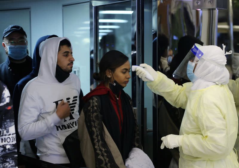 Passengers coming from China wearing masks to prevent a new coronavirus are checked by Saudi Health Ministry employees upon their arrival at King Khalid International Airport, in Riyadh