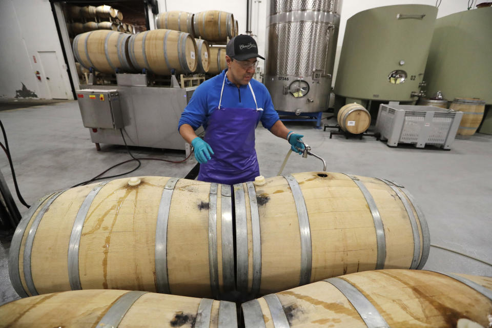 In this photo taken Thursday, Nov. 21, 2019, worker Jay Carlson tops off barrels of wine at Chateau Ste. Michelle winery in Woodinville, Wash. From less than 20 wineries in 1981, the Washington wine industry has grown to more than 1,000 this year. Experts say most of the industry’s success stems from the state’s climate and soils. (AP Photo/Elaine Thompson)