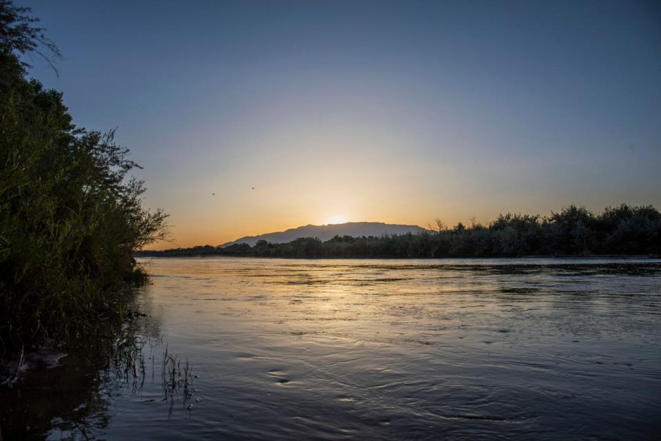 The Rio Grande flows near Albuquerque as the sun rises over the Sandia Mountains.