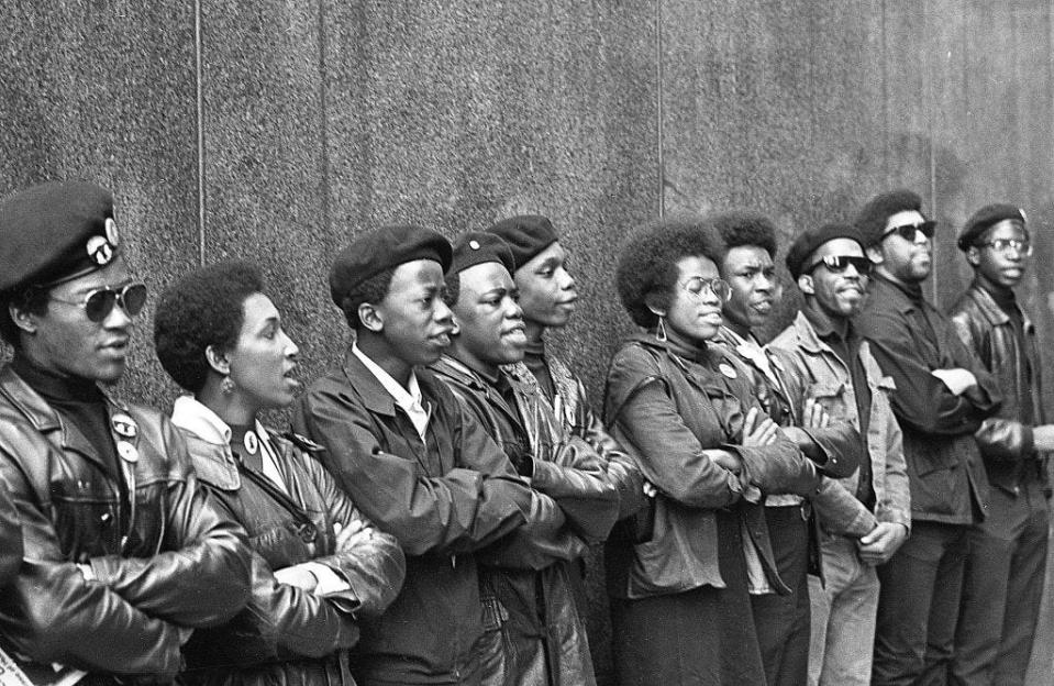 View of a line of Black Panther Party members as they demonstrate, arms folded, outside the New York County Criminal Court (at 100 Court Street), New York, New York, April 11, 1969. The demonstration was about the 'Panther 21' trial, over jailed Black Panther members accused of shooting at police stations and a bombing; all of whom were eventually acquitted.