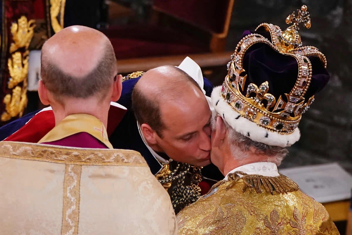 Britain's Prince William, Prince of Wales kisses his father, Britain's King Charles III, wearing St Edward's Crown, during the King's Coronation Ceremony (POOL/AFP via Getty Images)