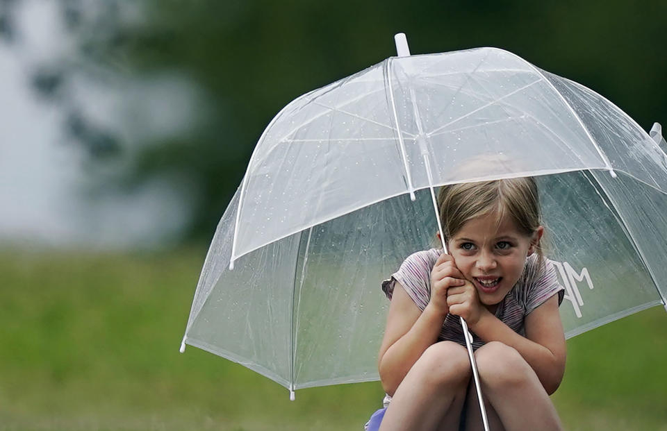 Joie Pearson, 5, uses an umbrella to keep dry during a light rain during the final round of the Byron Nelson golf tournament in McKinney, Texas, Sunday, May 14, 2023. (AP Photo/LM Otero)