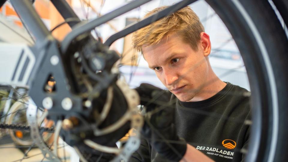 Im Februar hat er seine Ausbildung zum Zweiradmechatroniker abgeschlossen: Stefan Borschert setzt ein neues Hinterrad an einem E-Lastenrad ein.