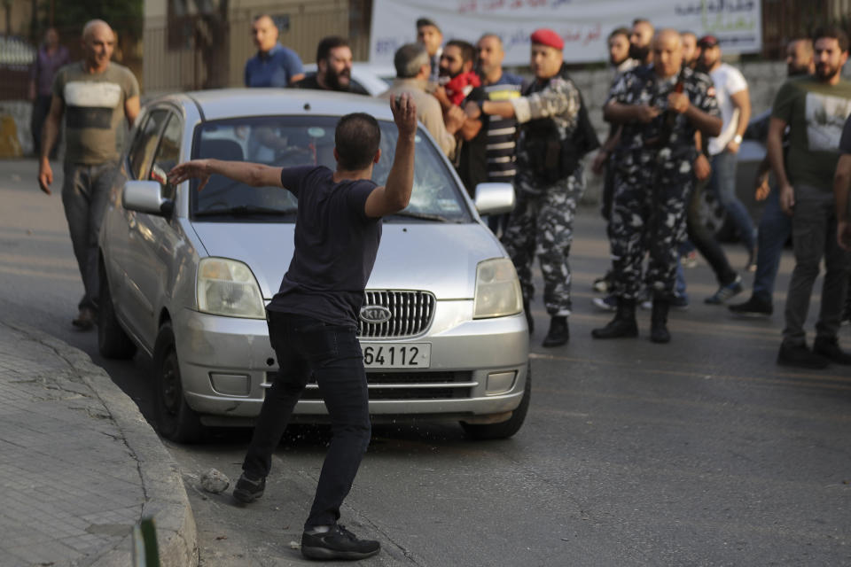 Anti-Government protesters throw stones at the car belonging to a supporter of President Michel Aoun, with whom they found an automatic rifle used in a shooting in the town of Jal el-Dib, north of Beirut, Lebanon, Wednesday, Nov. 13, 2019. A man opened fire over the heads of protesters in a town north of Beirut Wednesday, the second shooting incident in as many days as tensions rise in Lebanon between supporters and opponents of President Michel Aoun amid nationwide protests. (AP Photo/Hassan Ammar)