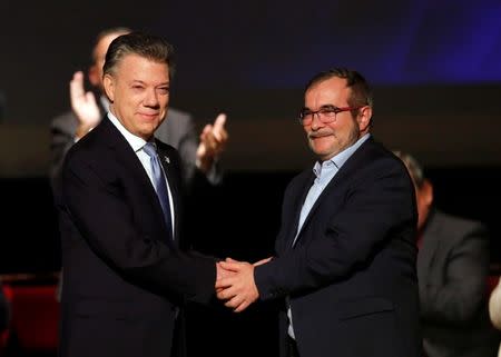Colombia's President Juan Manuel Santos and Marxist FARC rebel leader Rodrigo Londono, known as Timochenko, shake hands after signing a peace accord in Bogota, Colombia November 24, 2016. REUTERS/Jaime Saldarriaga