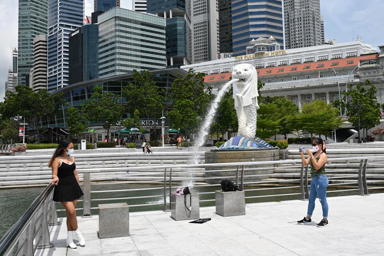 People take pictures in front of the Merlion statue in Singapore on May 5, 2021. (Photo by ROSLAN RAHMAN / AFP) (Photo by ROSLAN RAHMAN/AFP via Getty Images)