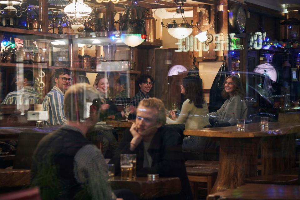 People sit in a bar in Stockholm, Wednesday, March 25, 2020. The streets of Sweden's capital are quiet but not deserted. Sweden has some of the most relaxed measures in Europe in the fight against the coronavirus outbreak. So far, only gatherings of over 500 people are banned and elementary and middle schools remain open. The new coronavirus causes mild or moderate symptoms for most people, but for some, especially older adults and people with existing health problems, it can cause more severe illness or death. (AP Photo/David Keyton)