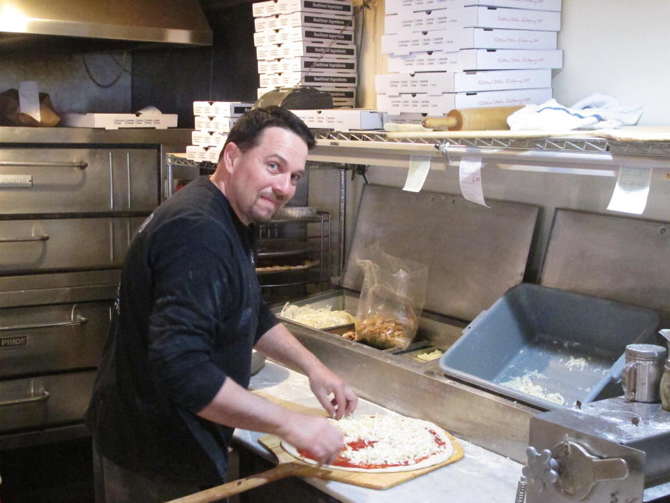 In this March 24, 2020, photo, Michael Morin, co-owner of Federico's Pizza in Belmar N.J., makes a pizza. Morin and his brother Bryan took out a $50,000 line of credit to ensure that their employees can stay on the payroll for at least two months during the virus outbreak. That prompted an outpouring of donations from customers wanting to send pizzas to hospital workers and first responders. (AP Photo/Wayne Parry)