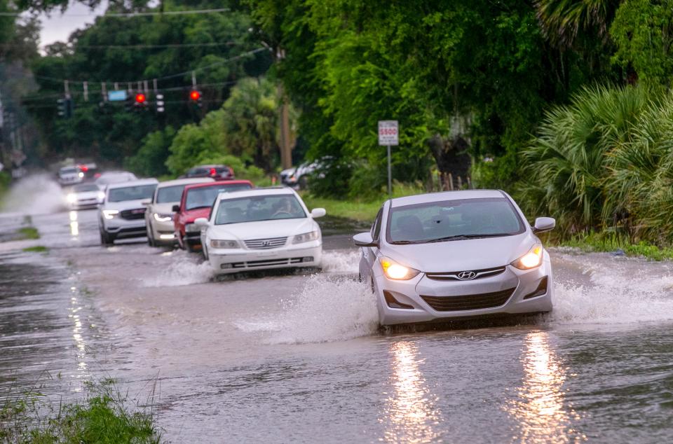 Cars manage the flooded road on Southwest 27th Avenue near Southwest 66th Street on Tuesday.