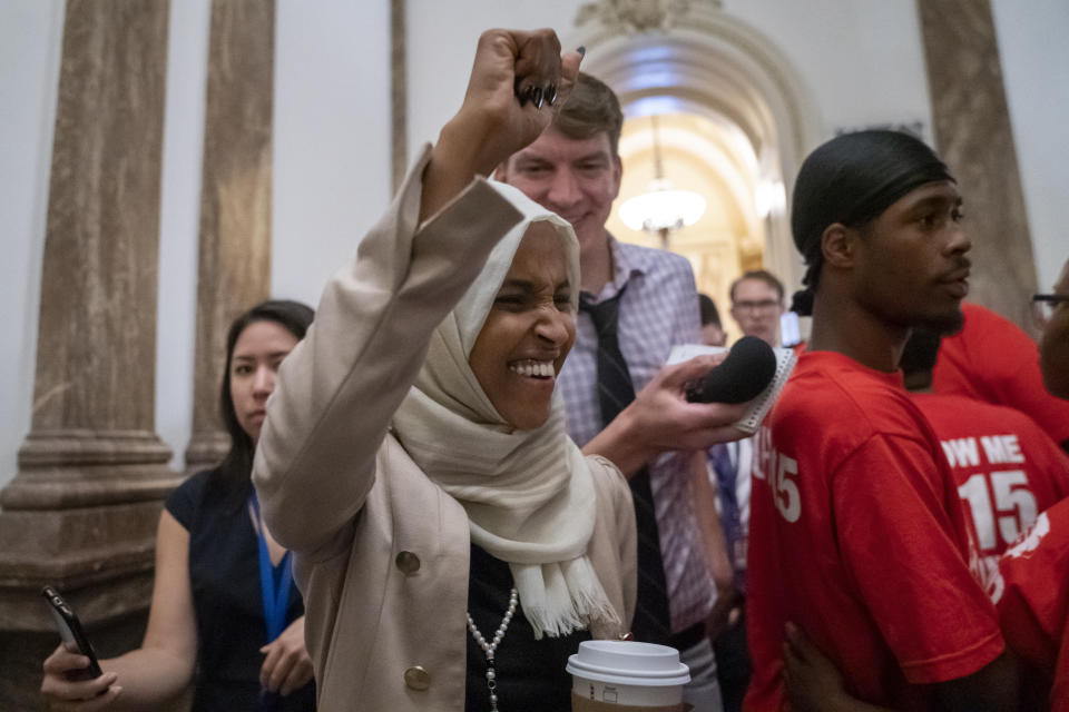 Rep. Ilhan Omar, D-Minn., a target of racist rhetoric from President Donald Trump, responds to cheers from visitors at the Capitol seeking a raise in the minimum wage, as she leaves the chamber following votes, in Washington, Thursday, July 18, 2019. (AP Photo/J. Scott Applewhite)