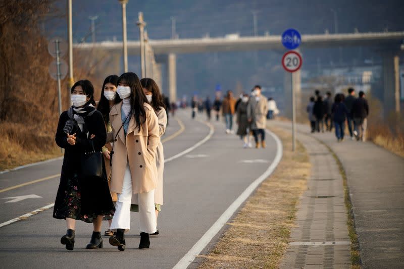 Women wearing masks to prevent contracting the coronavirus take a walk at a Han River park in Namyangju