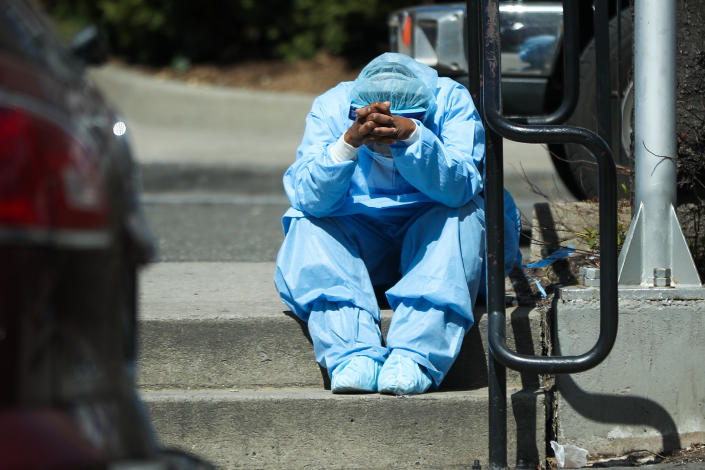 A health care worker sits by the Brooklyn Hospital Center in New York early in the COVID-19 pandemic in 2020. 