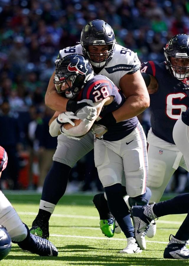 Houston Texans running back Rex Burkhead (28) is stopped by Seattle Seahawks defensive tackle Al Woods (99) during the first half of an NFL football game, Sunday, Dec. 12, 2021, in Houston. (AP Photo/Eric Christian Smith)