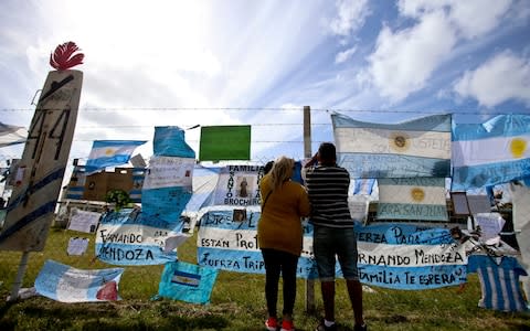 Friends and family of missing submarine crew members place a flag on the fence of the naval base in Mar de Plata, Argentina