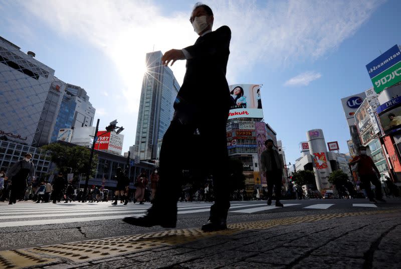 FILE PHOTO: A passersby wearing a protective face mask walks on the Shibuya crossing, amid the coronavirus disease (COVID-19) outbreak, in Tokyo