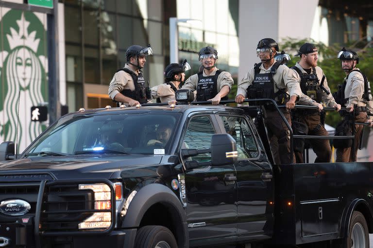 Miembros de las fuerzas del orden que usan equipo antidisturbios pasan por el tribunal donde se presentará Trump