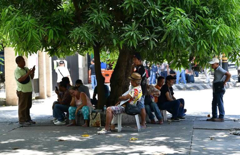 Des habitants s'abritent des fortes chaleurs sous l'ombre d'un arbre à Manille, le 24 avril 2024 aux Philippines (Ted ALJIBE)