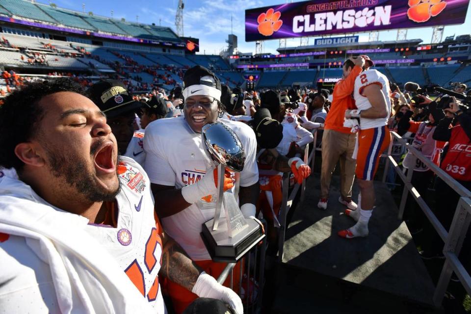 Clemson Tigers offensive lineman Bryn Tucker (73) and offensive lineman Zack Owens (72) celebrate with the Gator Bowl trophy while Clemson Head Coach Dabo Swinney hugsClemson Tigers quarterback Cade Klubnik (2) after the team’s close victory over Kentucky. The Kentucky Wildcats faced off against the Clemson Tigers Friday, December 29, 2023, in the TaxSlayer Gator Bowl in Jacksonville, Florida. The Wildcats led 14 to 10 at the half but the Tigers fought back and came away with a 38 to 35 victory. [Bob Self/Florida Times-Union]