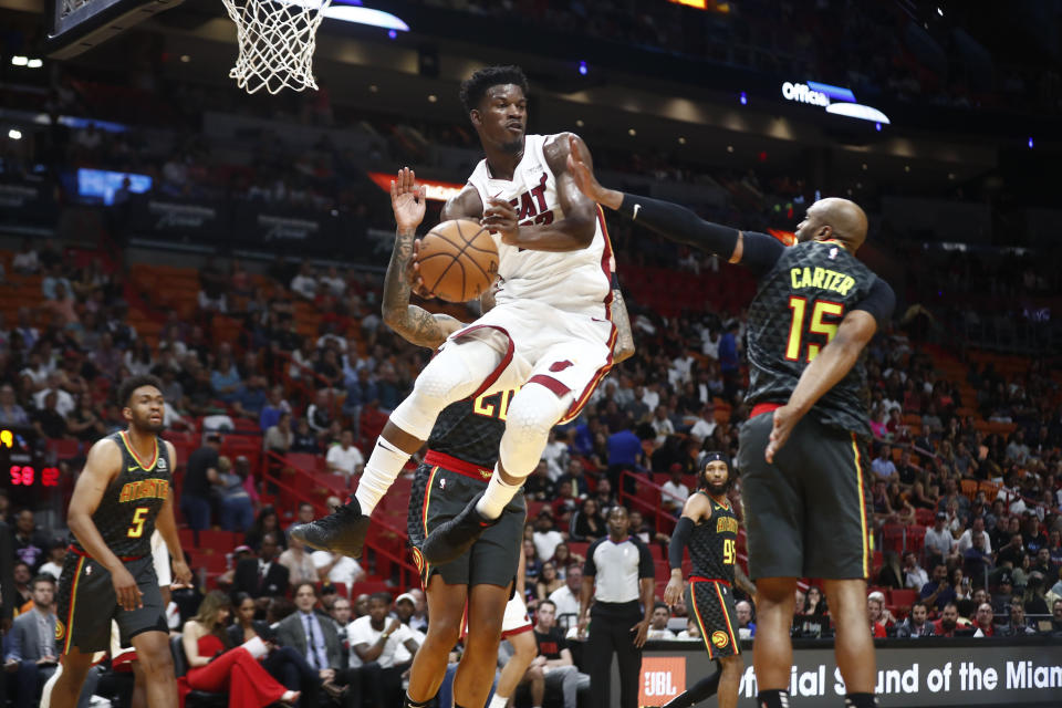 Miami Heat forward Jimmy Butler (22) passes the ball against Atlanta Hawks guard Vince Carter (15) during the second half of an NBA preseason basketball game Monday, Oct. 14, 2019, in Miami. (AP Photo/Brynn Anderson)