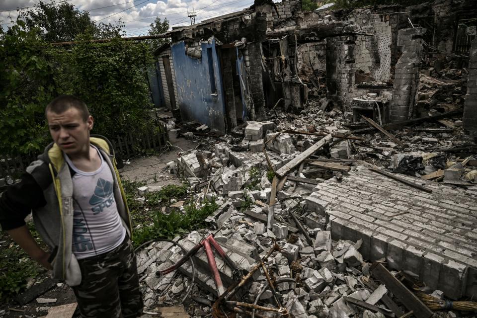 Ivan Sosnin, 19, stands in front of his destroyed house in the city of Lysychansk at the eastern Ukrainian region of Donbas on 7 June (AFP via Getty Images)