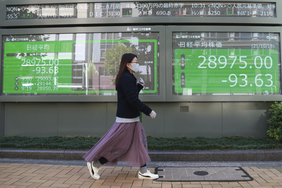 A woman walks by an electronic stock board of a securities firm in Tokyo, Monday, Oct. 18, 2021. Asian shares were mostly lower on Monday after China reported its economy grew at a meager 4.9% annual pace in July-September. (AP Photo/Koji Sasahara)