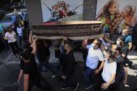 Mourners carry the coffin of Ibrahim Harb, 35, who was critically injured in the massive explosion at Beirut's port last year and who died on Monday nearly 14 months after the blast, as other throw rice during his funeral procession in Beirut, Lebanon, Tuesday, Sept. 28, 2021. On Aug. 4, 2020, hundreds of tons of ammonium nitrate, a highly explosive material used in fertilizers, ignited after a massive fire at the port. The death brings to at least 215 the number of people who have been killed by the blast, according to official records. (AP Photo/Hussein Malla)