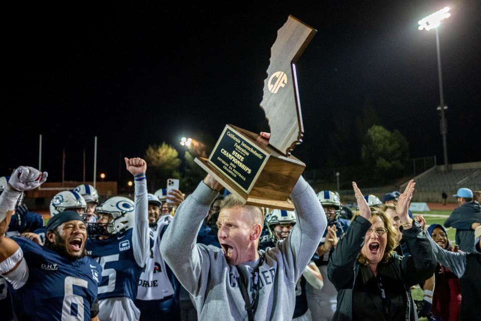 Central Valley Christian head coach Mason Hughes lifts the trophy after beating Los Gatos 45-42 in the CIF State Football Championship at Pasadena City College in Pasadena CA on Saturday, Dec. 09, 2023.
