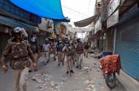 A police officer asks residents to not come out from their homes as they patrol in a lane after clearing the site of the longest-running protest against a new citizenship law following the lockdown by Delhi state government, in New Delhi