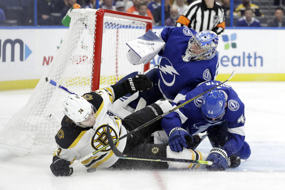 Boston Bruins left wing Jake DeBrusk (74) gets hit by Tampa Bay Lightning defenseman Jan Rutta (44) as they crash into goaltender Andrei Vasilevskiy (88) during the third period of an NHL hockey game Thursday, Dec. 12, 2019, in Tampa, Fla. (AP Photo/Chris O'Meara)