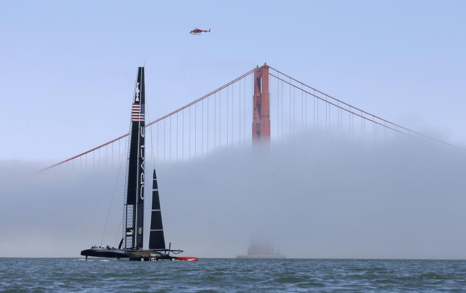 An Oracle Team USA catamaran makes its way past the Golden Gate Bridge in the fog during training for the America's Cup, Wednesday, July 3, 2013, in San Francisco. Opening ceremonies for the sailing event are scheduled for Thursday. (AP Photo/Eric Risberg)