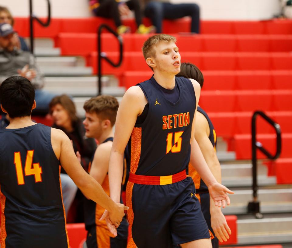 Seton junior Mason Harvey high-fives his teammates during starting lineups before a Bob Wettig Memorial Tournament game against Greensburg Dec. 27, 2022.