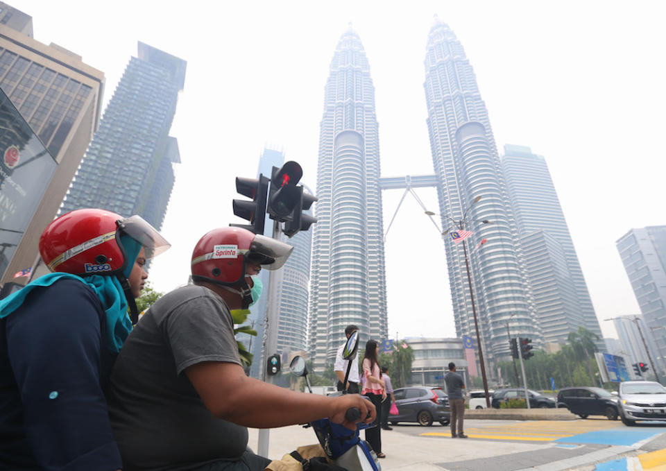 A motorist wears a mask as he travels past the Petronas Twin Towers shrouded in haze in Kuala Lumpur September 12, 2019. — Picture by Firdaus Latif