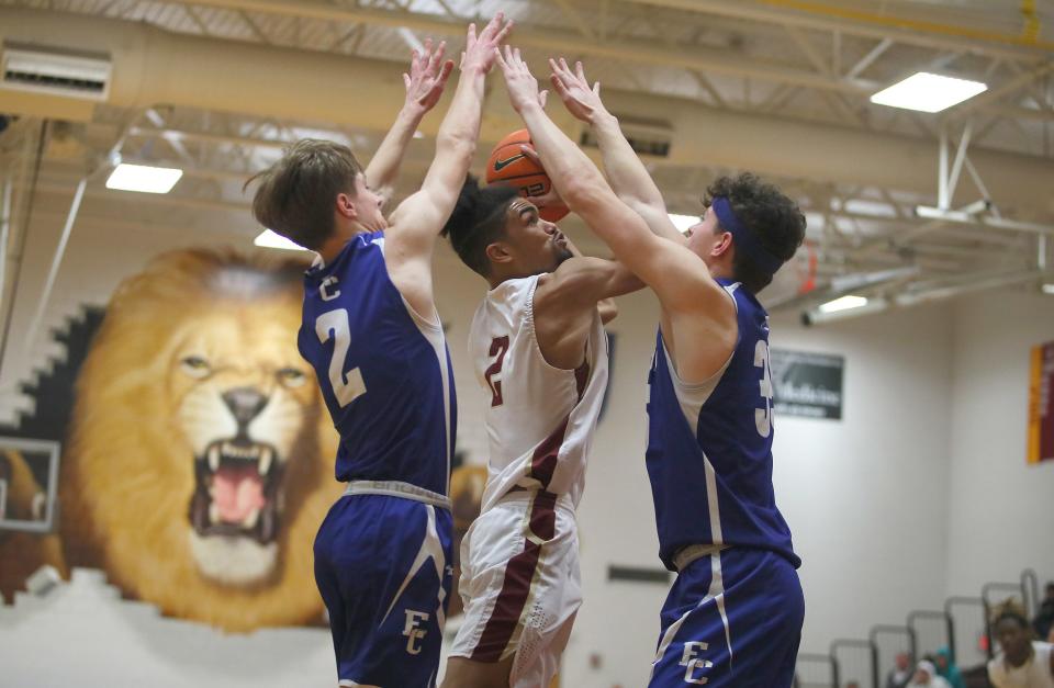 New Brighton's Trevon Phillips (center) attempts a layup while being heavily guarded by Ellwood City's Nathan Williams (left) and Joseph Roth (right) during the second half of the game Friday night at New Brighton Area High School.