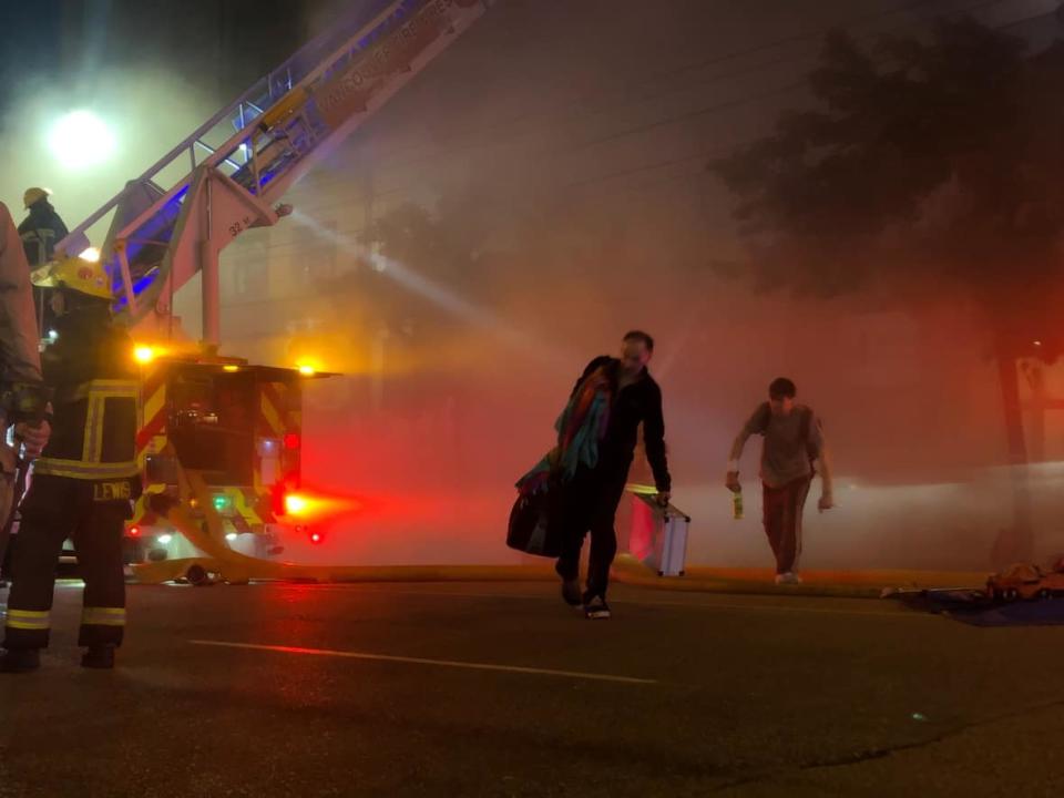 Residents of the 100-block of East Hastings Street leave with their belongings after a major fire broke out in a neighbouring building, the Downtown Eastside Street Church, around 9:30 p.m. on Wednesday. (David P. Ball/CBC - image credit)