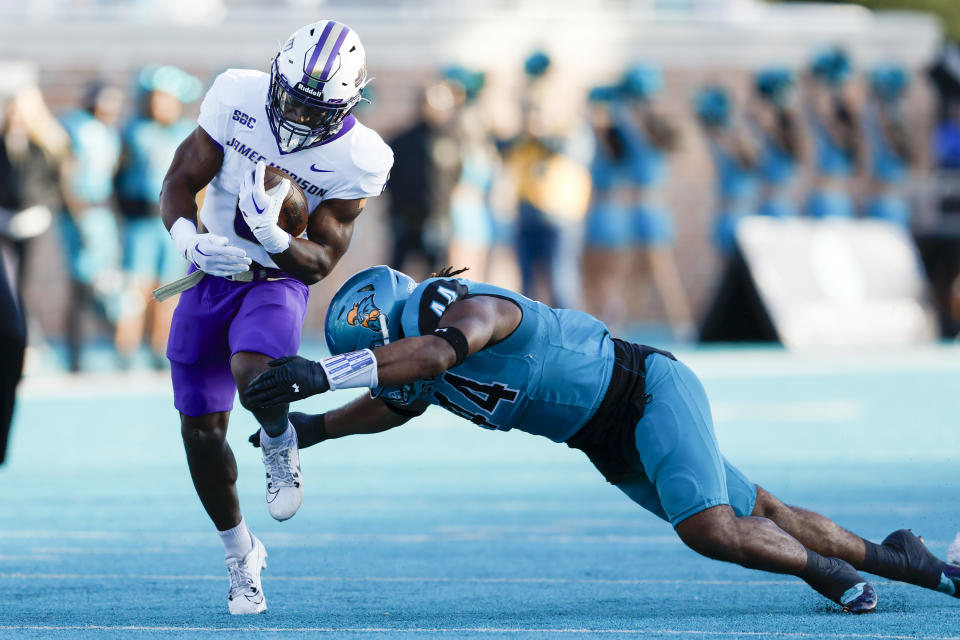 James Madison running back Kaelon Black, left, carries the ball as Coastal Carolina defensive lineman Will Whitson tries to make the tackle during the first half of an NCAA college football game in Conway, N.C., Saturday, Nov. 25, 2023. (AP Photo/Nell Redmond)