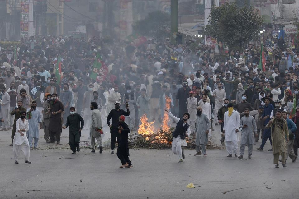 Supporters of former Pakistani Prime Minister Imran Khan's party, 'Pakistan Tehreek-e-Insaf' throw stones toward police officers during a protest to condemn a shooting incident on their leader's convoy, in Rawalpindi, Pakistan, Friday, Nov. 4, 2022. Khan who narrowly escaped an assassination attempt on his life the previous day when a gunman fired multiple shots and wounded him in the leg during a protest rally is listed in stable condition after undergoing surgery at a hospital, a senior leader from his party said Friday. (AP Photo/Mohammad Ramiz)