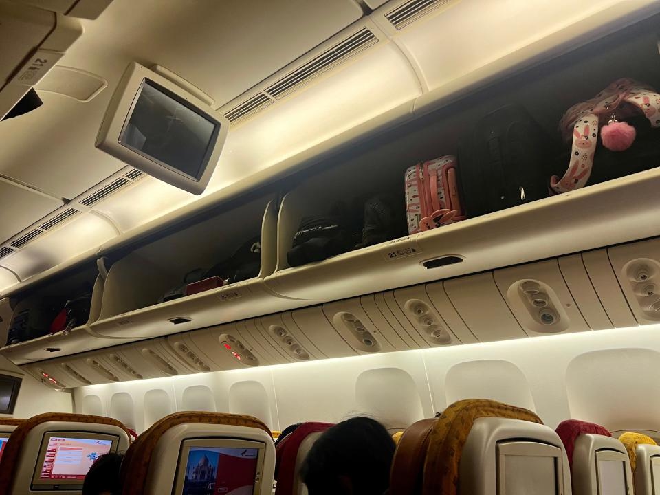 The overhead bins with luggage.