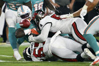 Miami Dolphins wide receiver DeVonte Dedmon (83) fumbles the football when he gets hit by Tampa Bay Buccaneers linebacker Jordan Young (57) and linebacker J.J. Russell (51) during the second half of an NFL preseason football game Saturday, Aug. 13, 2022, in Tampa, Fla. (AP Photo/Jason Behnken)