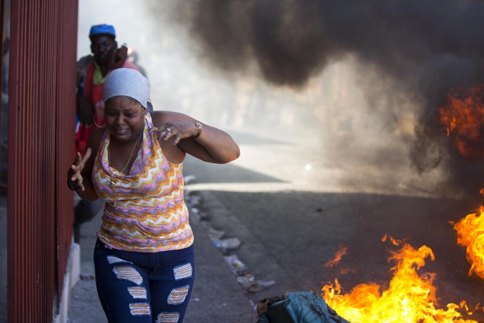 Residents run past burning barricades during a strike that is part of protests demanding to know how Petro Caribe funds have been used by the current and past administrations, in Port-au-Prince, Haiti, Monday, Nov. 19, 2018. Much of the financial support to help Haiti rebuild after the 2010 earthquake comes from Venezuela's Petro Caribe fund, a 2005 pact that gives suppliers below-market financing for oil and is under the control of the central government. (AP Photo/Dieu Nalio Chery)