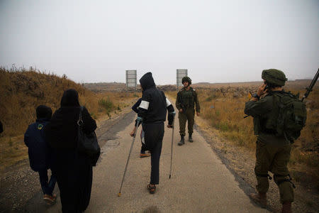 Syrians walk to a bus just after they crossed the armistice line from Syria to the Israeli-occupied Golan Heights to get medical treatment in Israel, July 11, 2018. REUTERS/Ronen Zvulun