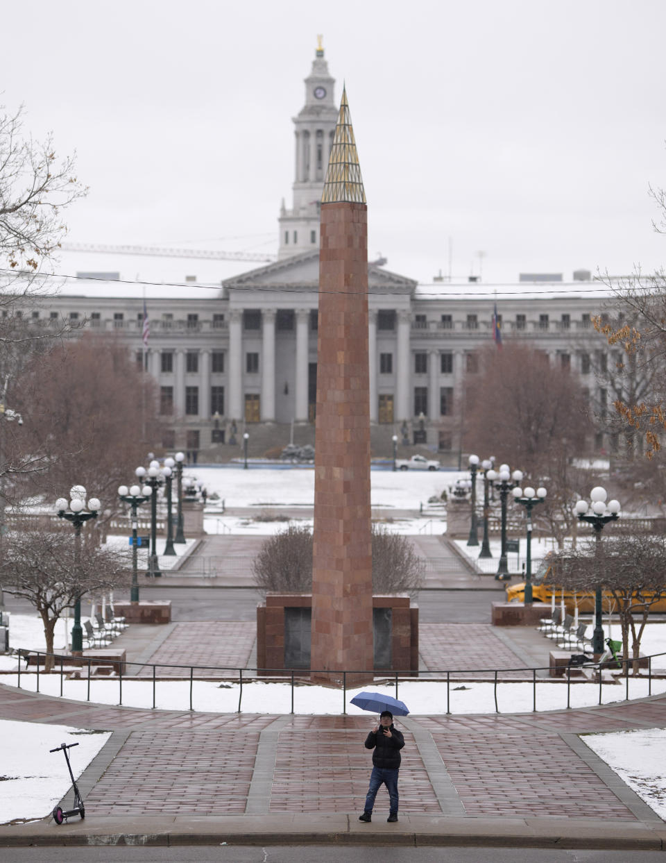 A pedestrian uses an umbrella for cover as a spring storm packing rain and light snow crossed the intermountain West Tuesday, April 4, 2023, in downtown Denver. (AP Photo/David Zalubowski)