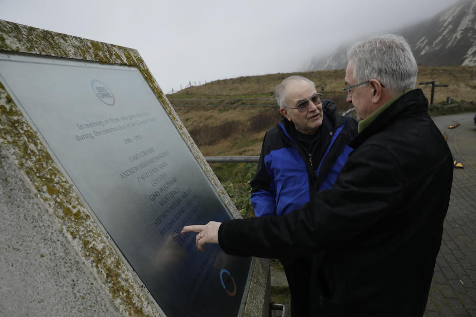 Former British Channel Tunnel worker Graham Fagg, left, and Former French Channel Tunnel worker Philippe Cozette look at a memorial plaque in memory of those workers who lost their lives during the construction of the Channel Tunnel, at Samphire Hoe, a site made from the disposal of the Channel Tunnel chalk marl spoil at the base of Shakespeare Cliff near Dover, England, after an interview with The Associated Press, Thursday, Jan. 30, 2020. By digging their way to each other deep under the English Channel, tunnelers Graham Fagg and Philippe Cozette became symbols for British-French friendship when they made the first breakthrough in the Channel Tunnel nearly 30 years ago. (AP Photo/Matt Dunham)