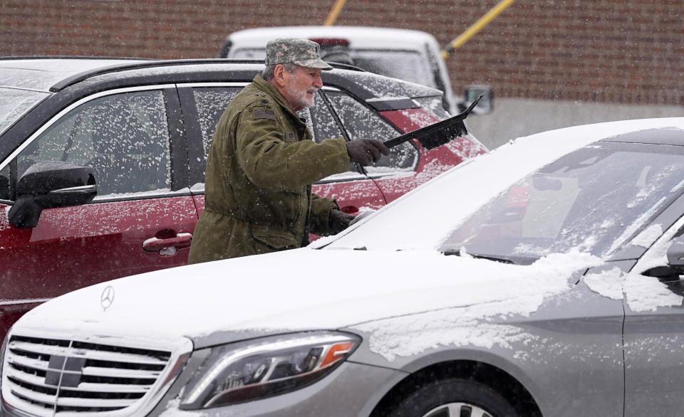 With the daytime high temperature in negative far below zero and a light snow falling, a motorist clears snow from the windscreen of a vehicle Monday, Jan. 15, 2024, in Denver. Forecasters predict that the frigid weather will persist until midweek in the intermountain West. (AP Photo/David Zalubowski)