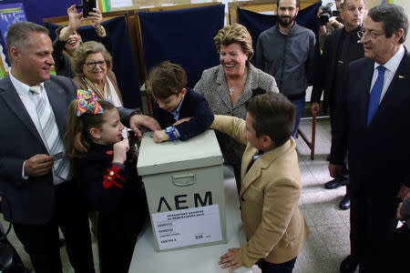 Presidential candidate Nicos Anastasiades (R) watches as his grandchildren play with the ballot box, during the second round of the presidential election in Limassol, Cyprus February 4, 2018. REUTERS/Yiannis Kourtoglou