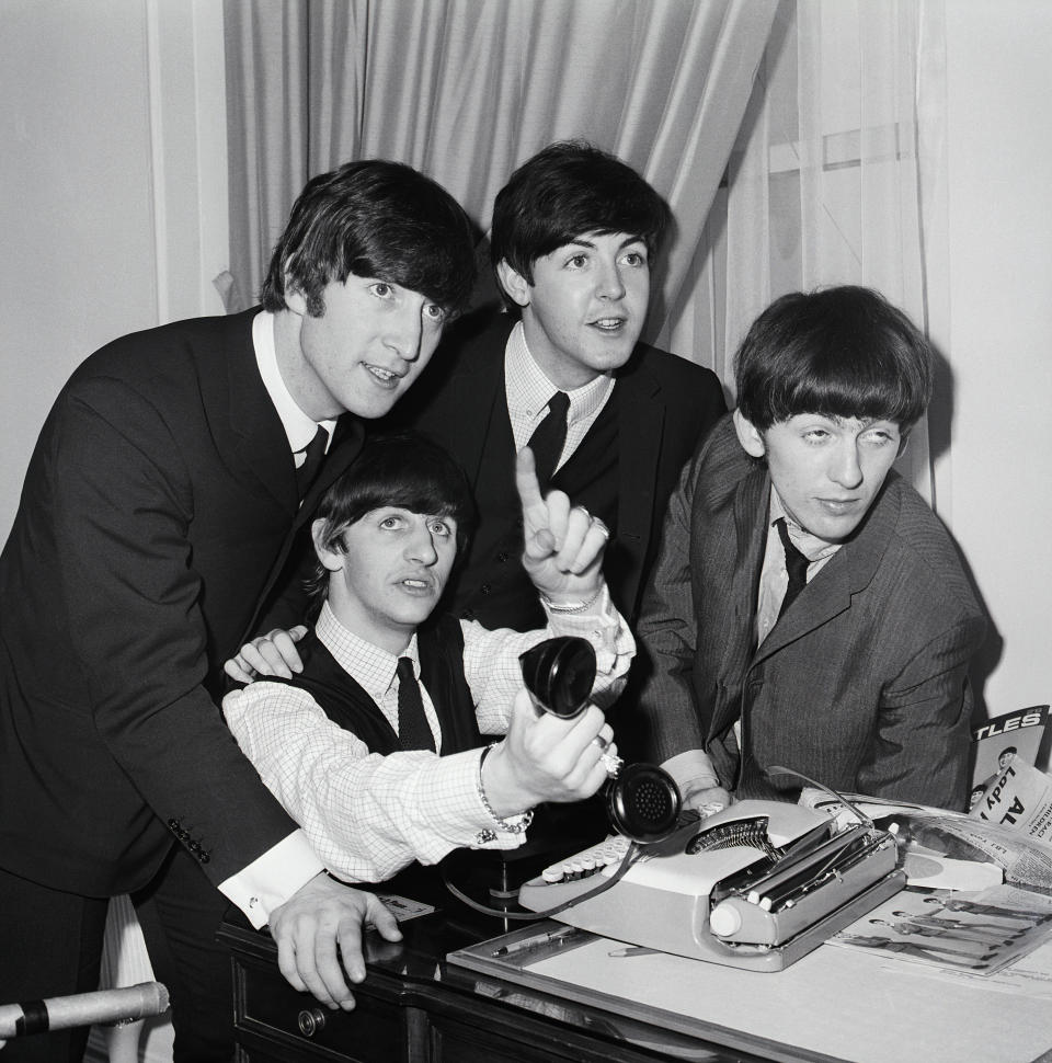 (Original Caption) 2/7/1964-New York, NY- The Beatles, Great Britain's gyrating song sensation, gather around phone in their Hotel Plaza suite after arriving in New York Feb. 7. Airport officials say thousands of teenage youths were on hand to greet the singers and accorded them the greatest reception ever rendered a theatrical personality. Seated at phone is Ringo Starr. Standing, left to right are: George Harrison, John Lennon and Paul McCartney.
