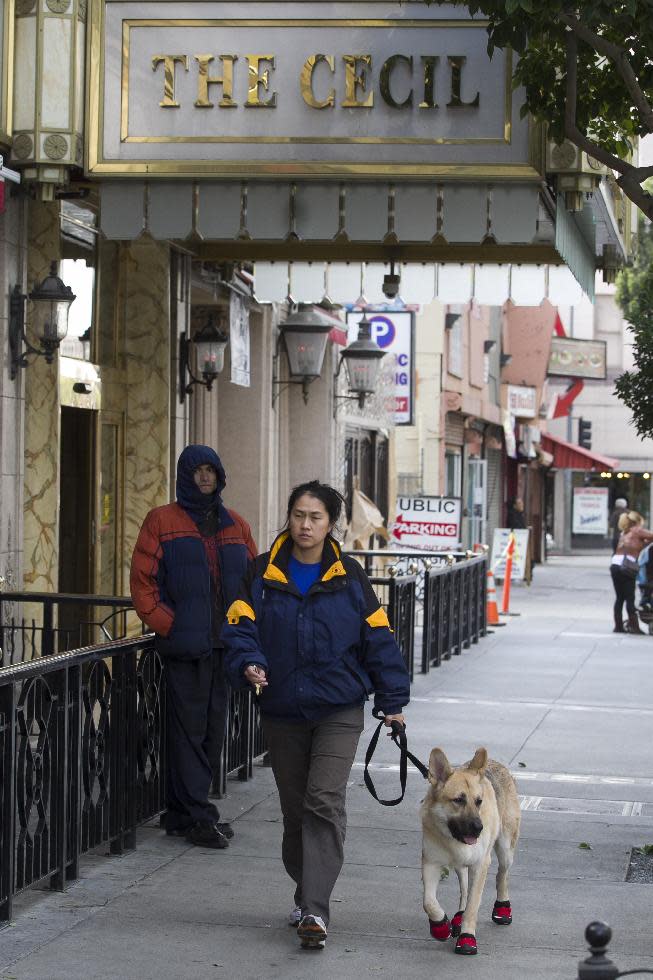Judy Lim walks with her dog Blitz past the Cecil Hotel in Los Angeles Thursday, Feb. 21, 2013. Canadian tourist Elisa Lam had been missing for about two weeks when officials at the Cecil Hotel found her body in a water cistern on the hotel roof. Guest complaints about low water pressure prompted a maintenance worker to make the gruesome discovery Tuesday, and officials were trying to determine if the 21-year-old was killed or if her death was a bizarre accident. (AP Photo/Damian Dovarganes)